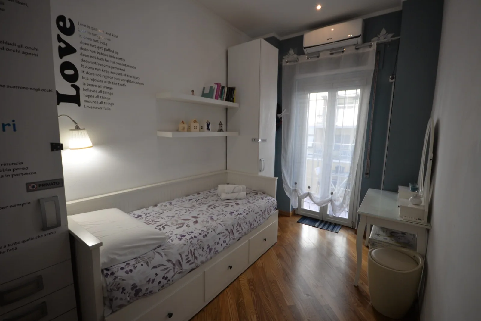 Cameretta luminosa con letto singolo, mensole a parete e finestra